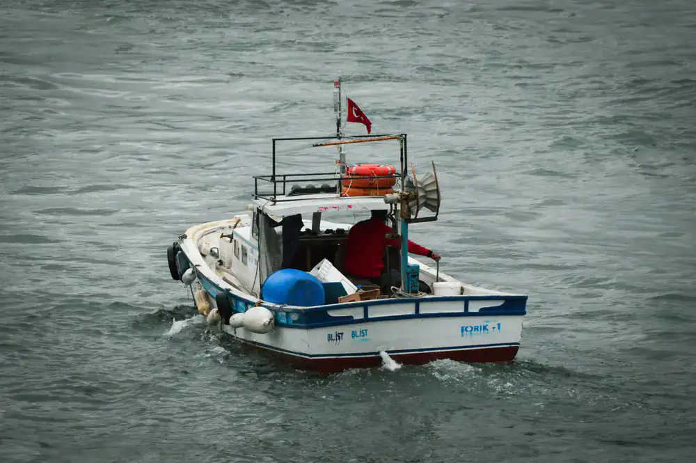 A larger keelboat cutting through gentle waves with a crew onboard