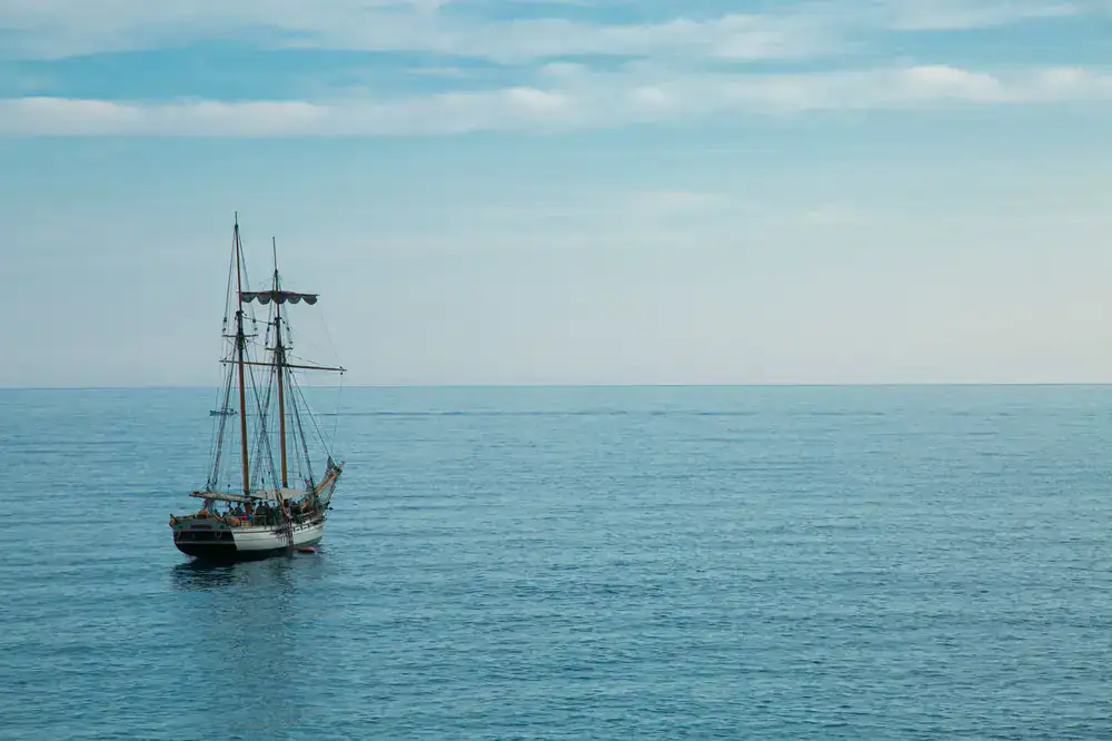 Sailboat navigating calm open waters under the sun